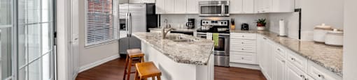 Spacious kitchen with island, granite countertops, custom home cabinets, smooth glass top stove, spacious pantries, and stainless-steel appliances at Tuscany Villas in Houston.