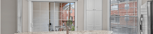 Spacious kitchen with island, granite countertops, custom home cabinets, French doors, smooth glass top stove, spacious pantries, and stainless-steel appliances at Tuscany Villas in Houston.