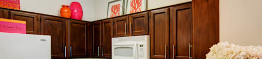 Spacious kitchen with honey brown toned cabinets with modern silver hardware, and white appliances