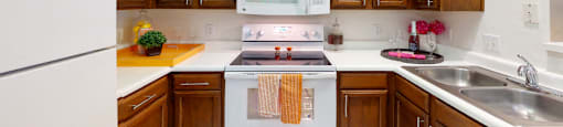 Spacious kitchen with honey brown toned cabinets with modern silver hardware, and white appliances.