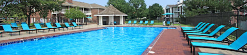 Huge swimming pool with spacious sundeck, poolside lounge chairs, beautiful landscaping, and scenic views at The Vanderbilt Apartments in Omaha, Nebraska