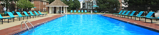 Huge swimming pool with spacious sundeck, poolside lounge chairs, beautiful landscaping, and scenic views at The Vanderbilt Apartments in Omaha, Nebraska
