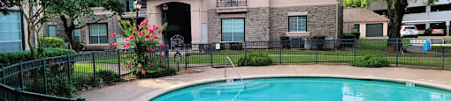 Luxury resort-style swimming pool with poolside lounges chairs, beautiful landscaping, lush landscaping and scenic views at Village on the Parkway Apartments.