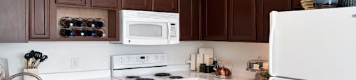Spacious kitchen with designer white appliances and tile floors at Village on the Parkway Apartments