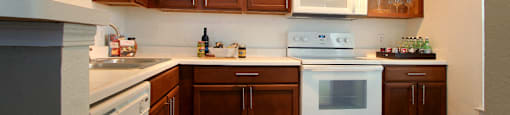 Spacious kitchen with designer white appliances and plank wood floors at Village on the Parkway Apartments.