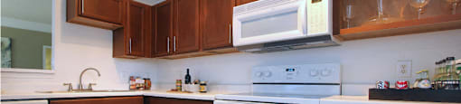 Spacious kitchen with designer white appliances and plank wood floors at Village on the Parkway Apartments.