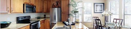 Luxury apartments in Houston with spacious kitchen and dining room with granite countertops, kitchen island, stainless steel appliances, oversized windows, lots of natural light, and hardwood floors.