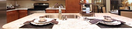 Luxury apartments next to the Galleria in Dallas with granite countertops, stainless steel appliances, built-in wine rack, kitchen island, and porcelain tile floor at Villa Piana Apartments in Dallas
