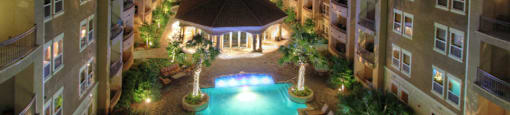 Luxury apartments with resort-style pool, palm trees, spacious sundeck with poolside lounge chairs, grilling station, fountains, and fitness center at Villa Piana Apartments in Dallas