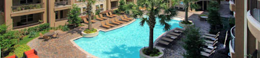 Luxury apartments with palm trees, spa, hot tub, spacious sundeck with poolside lounge chairs, beautiful landscaping, and fountains at Villa Piana Apartments in Dallas