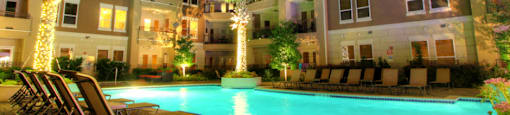 Luxury apartments with resort-style pool, palm trees, spacious sundeck with poolside lounge chairs, grilling station, fountains, and fitness center at Villa Piana Apartments in Dallas