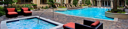 Luxury apartments with resort-style pool, spa, palm trees, spacious sundeck with poolside lounge chairs, grilling station, and fountains at Villa Piana Apartments in Dallas