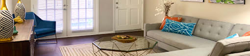 Spacious one and two bedroom floor plans with white brick accent walls, wood plank floors, and French doors at Waters of Winrock Apartments in Houston.