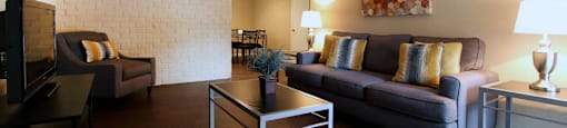 Spacious one and two bedroom floor plans with white brick accent walls and wood plank floors at Waters of Winrock Apartments in Houston.