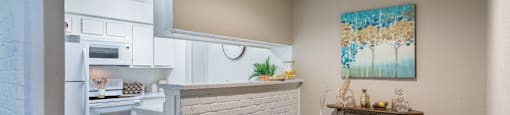 Spacious one and two bedroom floor plans with white brick accent walls and wood plank floors at Waters of Winrock Apartments in Houston
