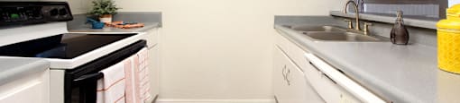 bright white kitchen with breakfast bar and wood plank floors at Woodlake on the Bayou Apartments