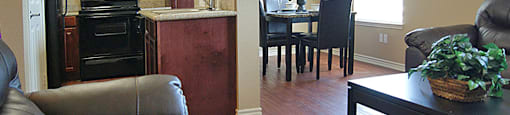 A kitchen with a refrigerator, oven, and a dining table with chairs.