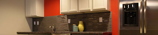 A kitchen with a red wall and a stainless steel refrigerator.