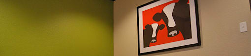 A picture of a cow is hanging on the wall above a table with chairs.