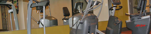 A gym with treadmills, elliptical machines and a fan.