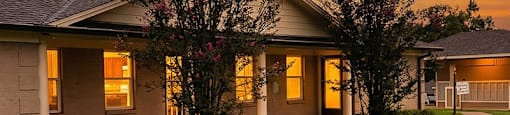 A building with a yellow door is surrounded by a grassy area.