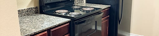 A kitchen with a black stove top oven and black refrigerator.