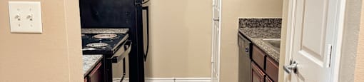A kitchen with a black fridge and wooden floors.