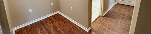 A room with wooden flooring and a door on the right.