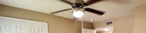 A room with a ceiling fan and wooden flooring.