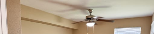 Empty room with a ceiling fan and a window.