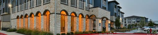 A modern building with a stone facade and arched windows.