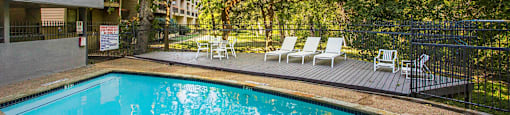 a swimming pool with chairs and a building in the background