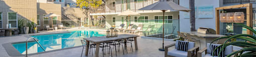 a swimming pool with a table and chairs in front of a building