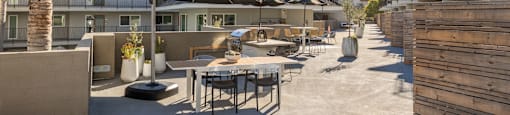 a patio area with tables and umbrellas at the enclave at university campuses