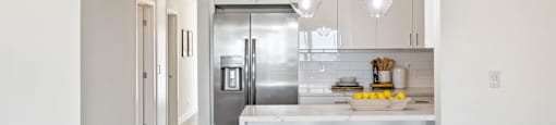 a kitchen with white cabinets and a bar with three stools