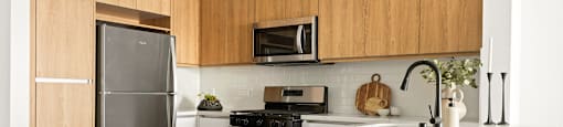 A kitchen with a refrigerator, microwave, and stove.