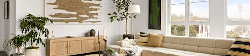 A living room with a large couch, a coffee table, and a wooden wall art.