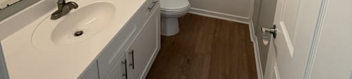 Park at Kirkstall 2-bed bathroom with wood floors and a white door.