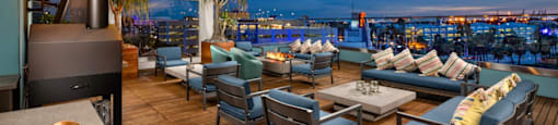 A wooden deck with blue chairs and a table with a bowl on it.
