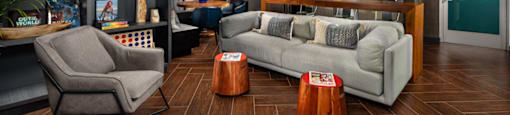 A modern living room with a grey chair, a white sofa, and a wooden floor.