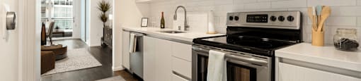 A modern kitchen with a black stove top oven and white cabinets.