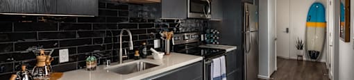 A modern kitchen with dark wood cabinets and a black backsplash.