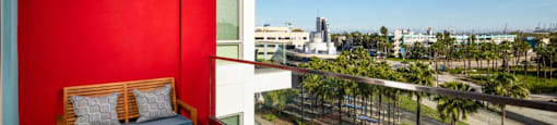 A balcony with a red wall and a view of the city.