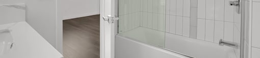 A white bathroom with a glass shower door and a white sink.