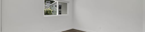 A room with a ceiling fan and a window showing a view of a building outside.