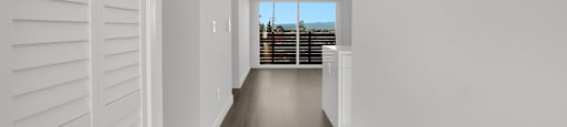 A long, narrow hallway with white walls and wooden flooring.