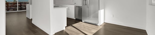 A modern kitchen with a refrigerator, cabinets, and a ceiling fan.