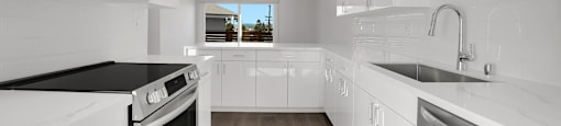 A modern kitchen with white cabinets and black countertops.