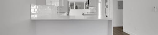 A modern kitchen with a long counter and pendant lights.