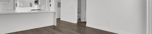 A spacious room with wooden flooring and white walls.